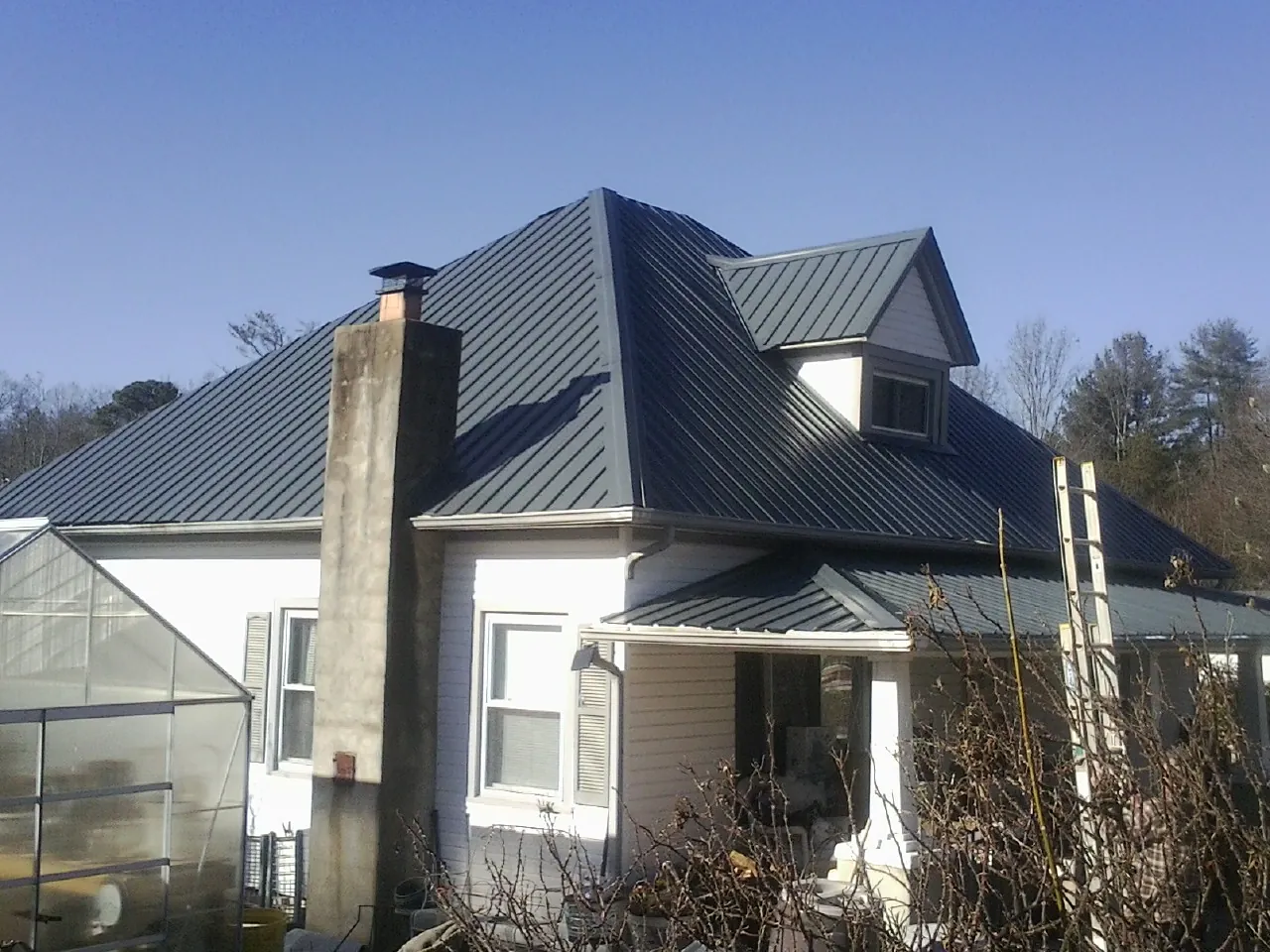 Dark blue standing seam metal roof on a white farmhouse with dormer — Slate & Tile Roof Repair by Roofing Brothers in Bedminster