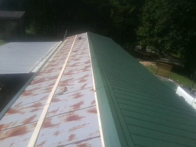 Old rusted panels beside newly installed green metal roofing — Wind Damage Roof Repair by Roofing Brothers in Bedminster