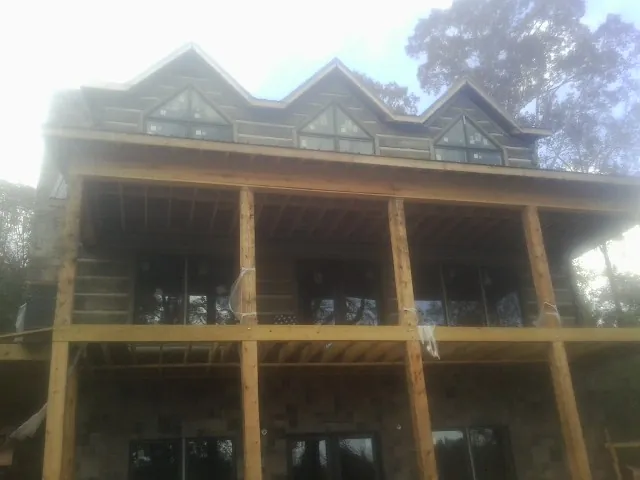 Dormers and porch framing on a large log home under construction — Roof Coating work by our crew in Bedminster