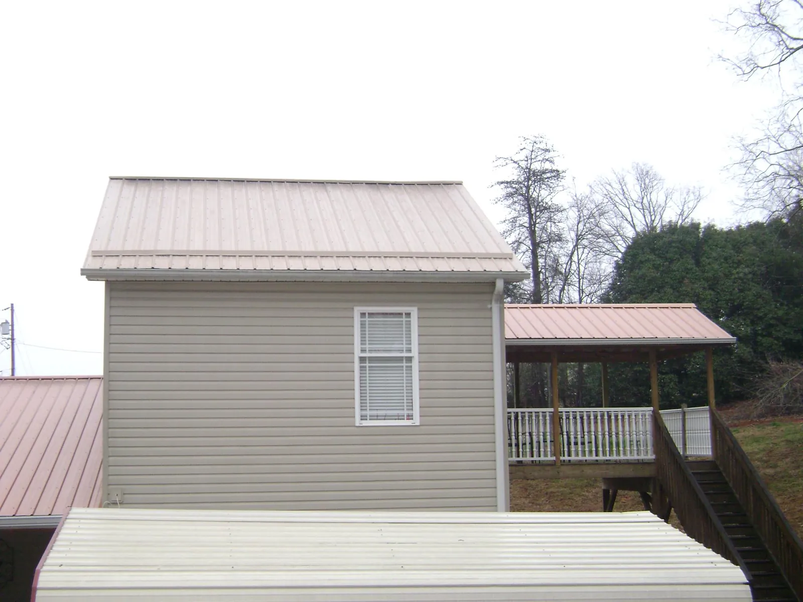Tan metal roofs on a two story addition and attached porch, from a Roof Replacement job in Bedminster